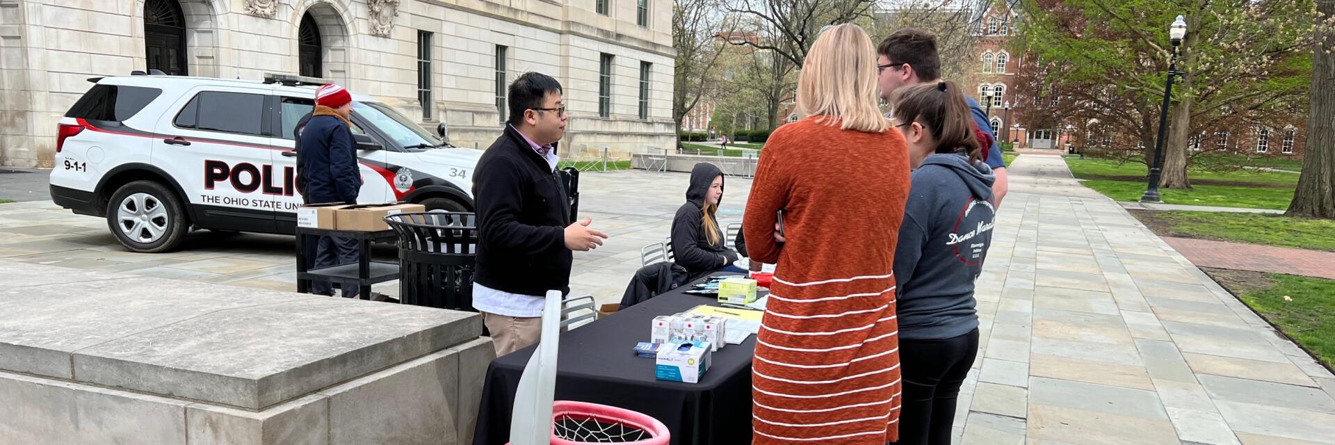 Students standing at outreach table disposing of unused medications.